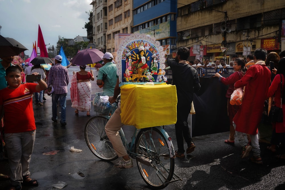 Un hombre montando en bicicleta por una calle junto a una multitud de personas