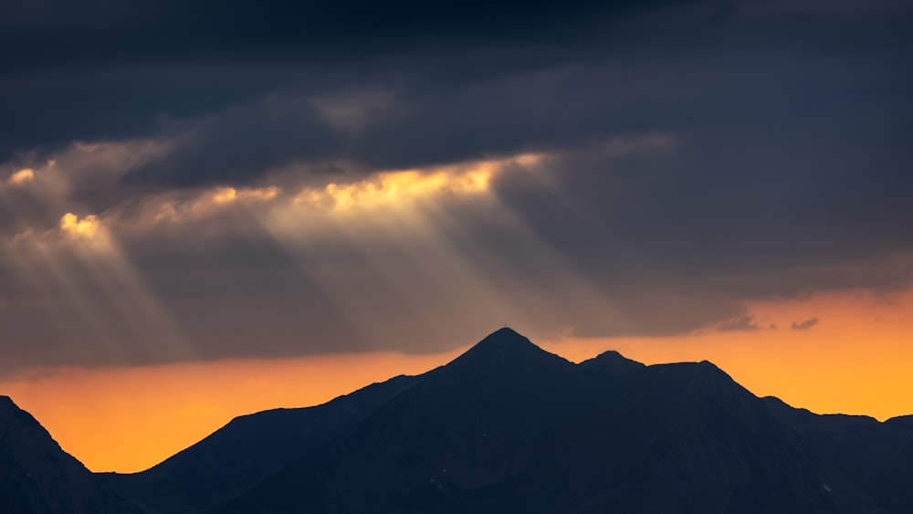 the sun is shining through the clouds over the mountains