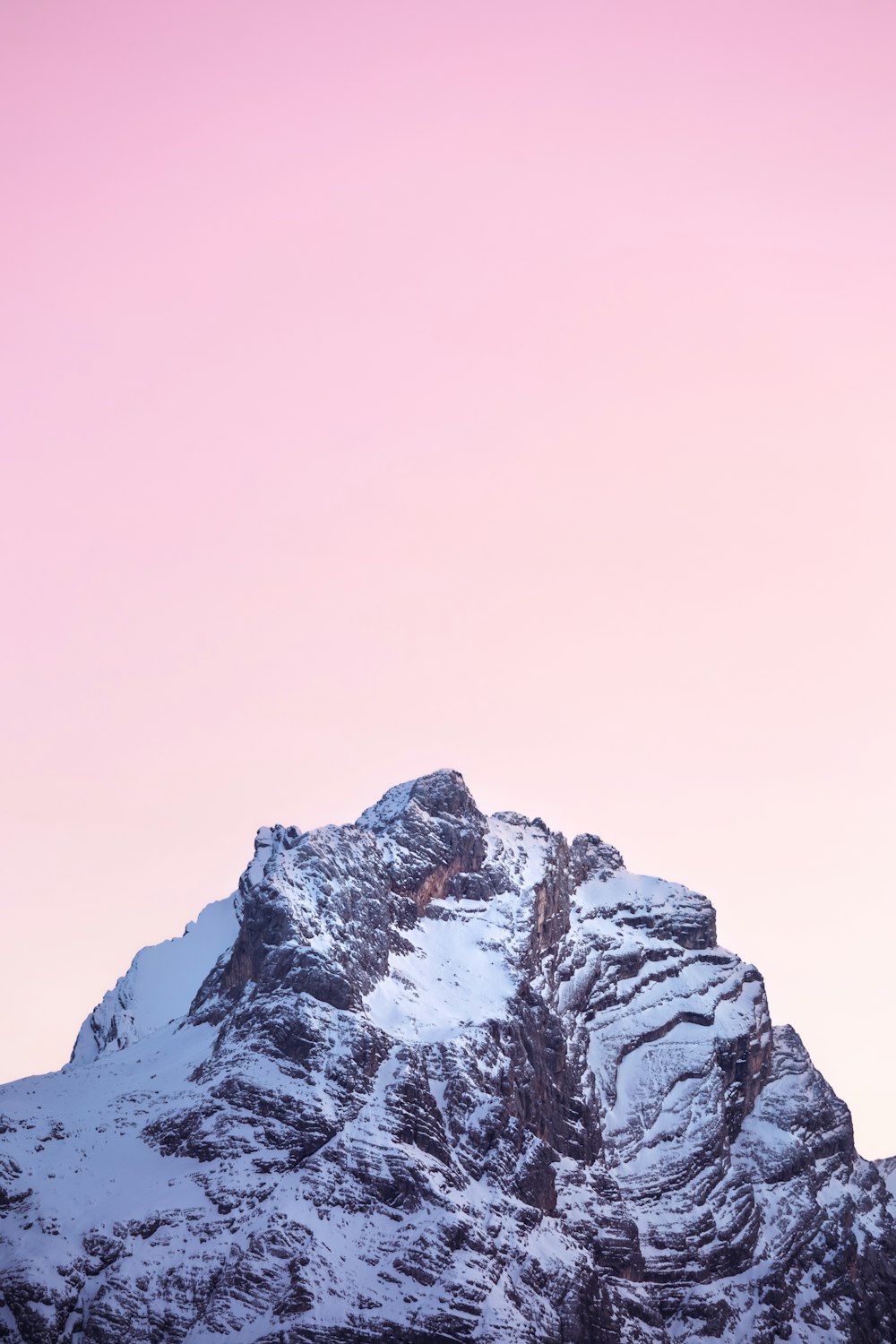 a snow covered mountain with a pink sky in the background