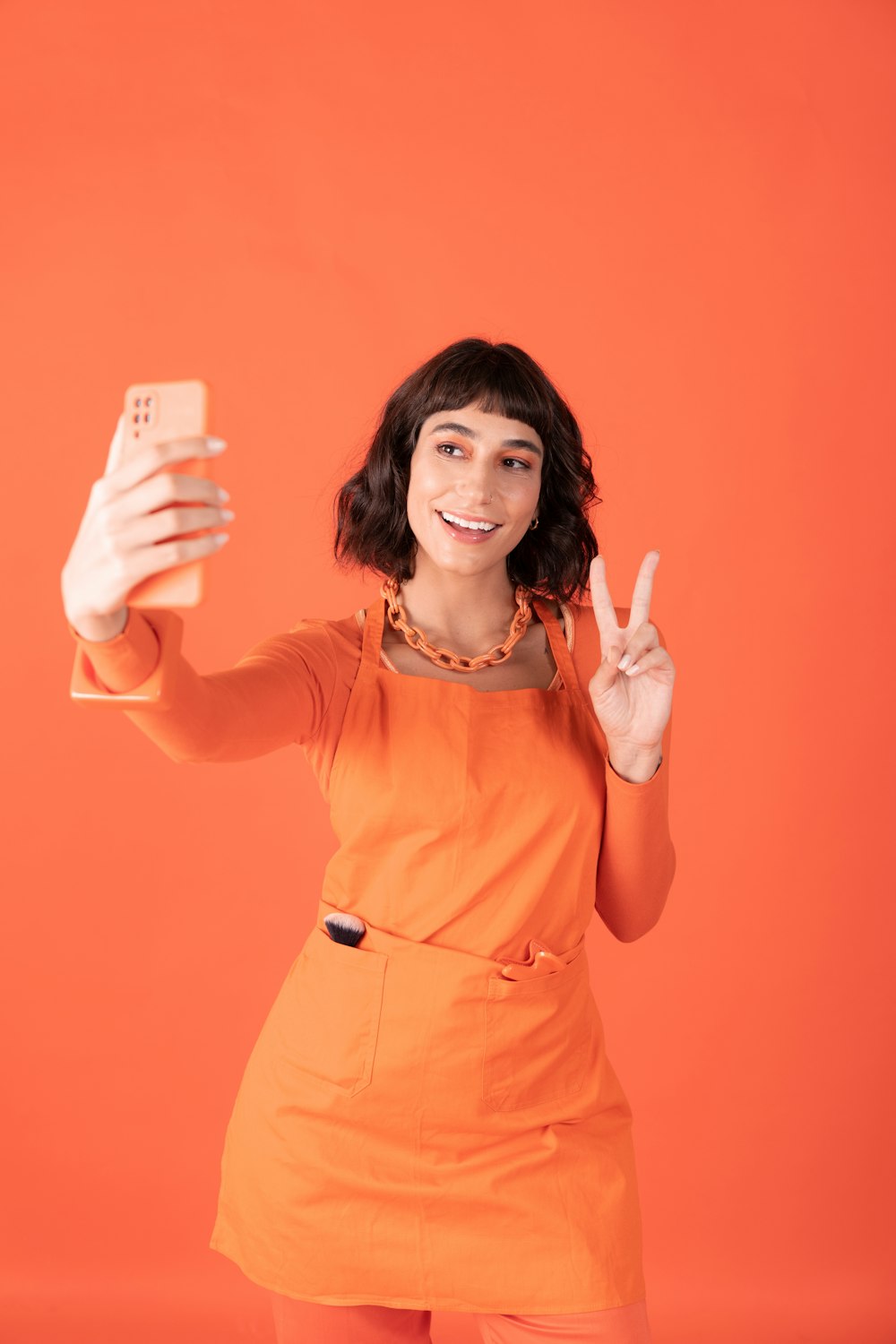 a woman in an orange dress holding a cell phone