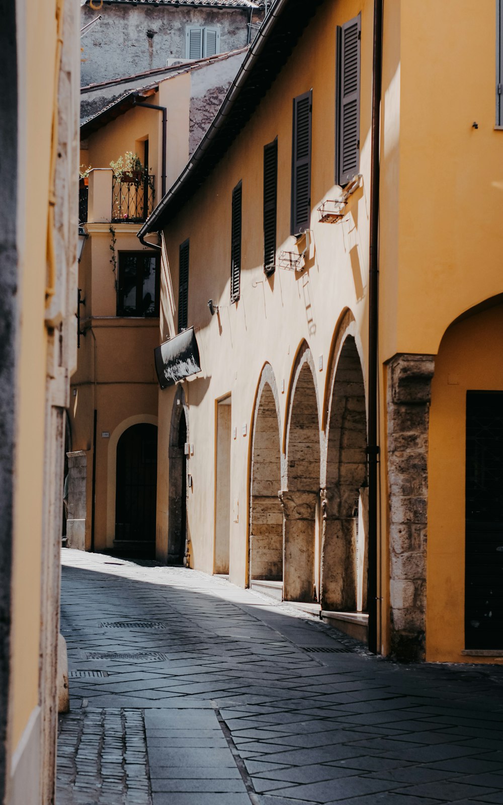 a narrow street lined with yellow buildings and arched doorways