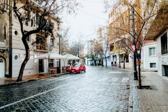 a red car parked on the side of a wet street