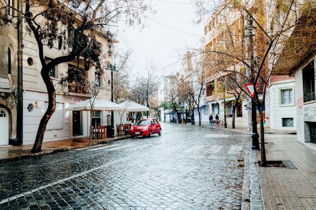 a red car parked on the side of a wet street