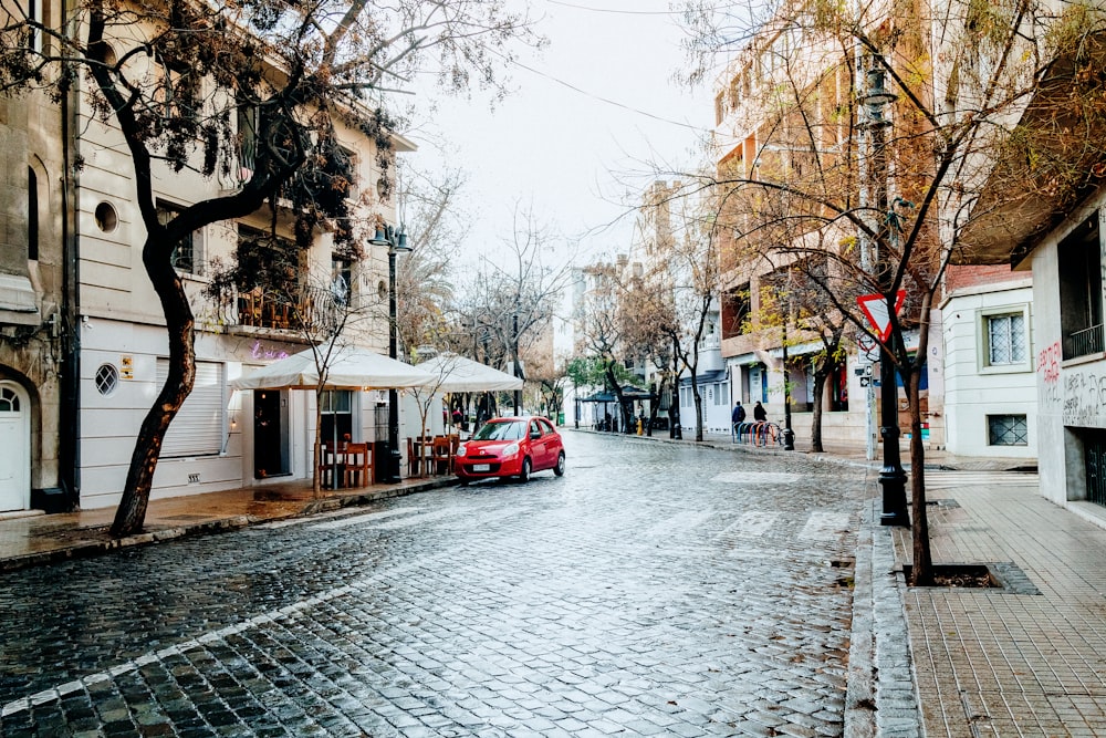 a red car parked on the side of a wet street