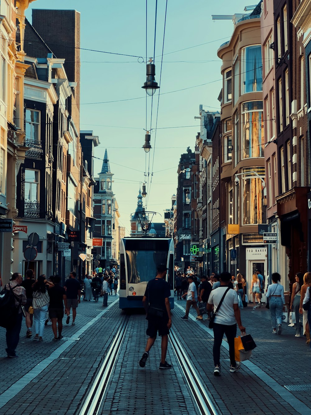 a group of people walking down a street next to tall buildings