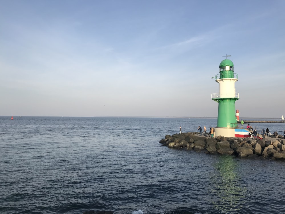 a green and white light house sitting on top of a pier