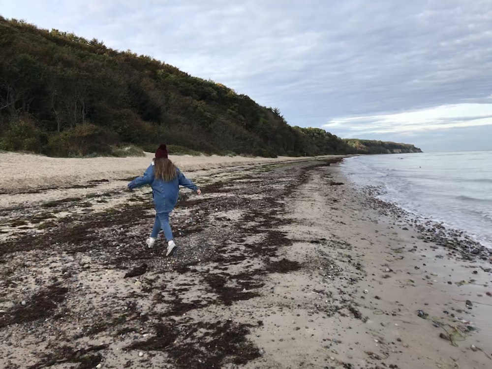 Una mujer caminando por una playa de arena junto al océano