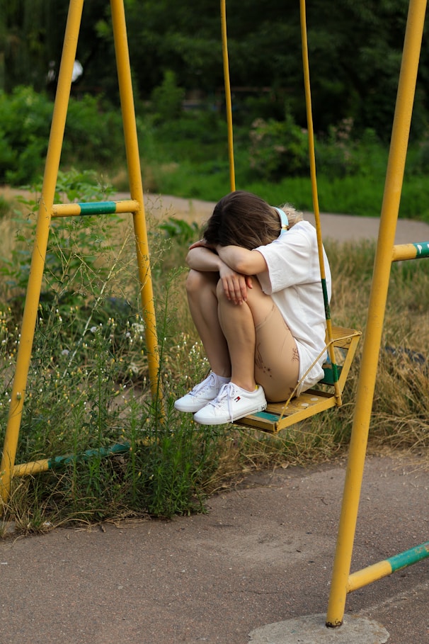 a woman sitting on a swing in a park