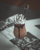 A rich chocolate milk tea with whipped cream and chocolate drizzle on top.