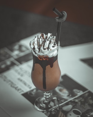 A rich chocolate milk tea with whipped cream and chocolate drizzle on top.