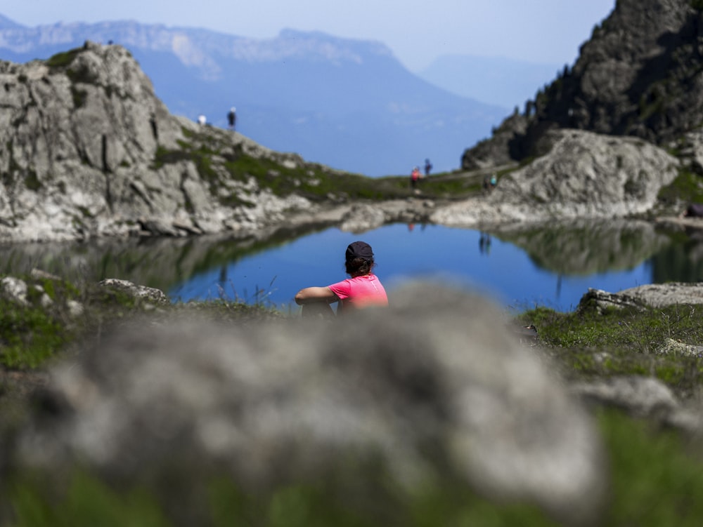 a person sitting in the grass near a body of water