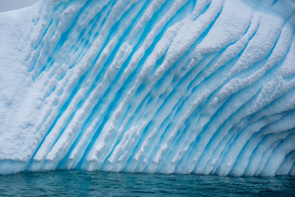 a large blue iceberg floating next to a body of water