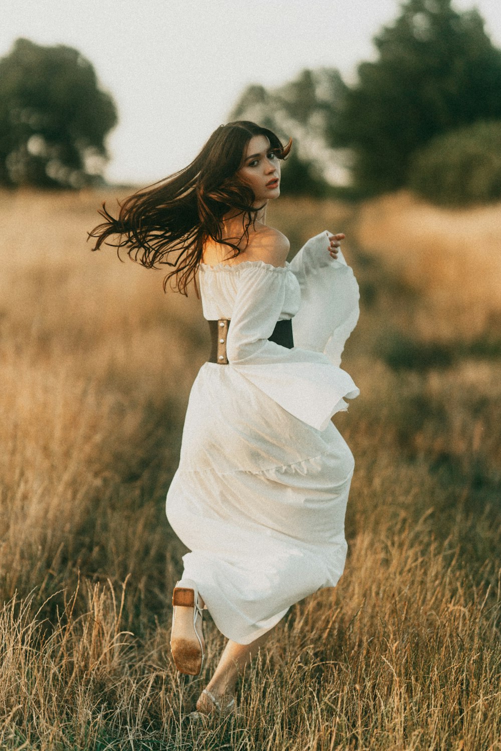 a woman in a white dress is running through a field