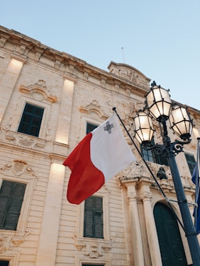 a flag hanging from a lamp post in front of a building