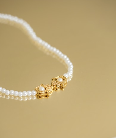 A delicate pearl necklace resting on a vintage wooden table