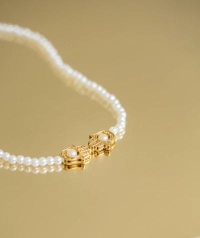 A stunning gold necklace with delicate pearls draped elegantly on a white silk cloth.