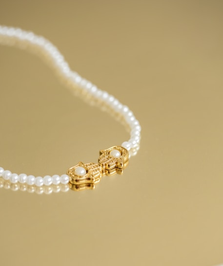 Close-up of a lustrous South Sea pearl necklace resting on soft ivory fabric with hints of gold and deep blue accents.