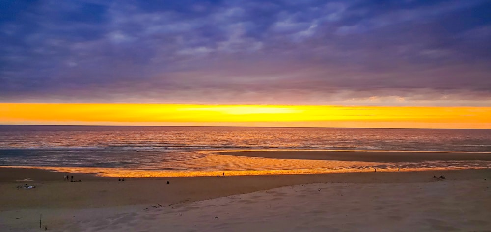 the sun is setting over the ocean on the beach