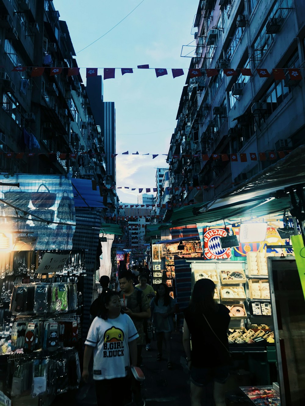 a group of people walking down a street next to tall buildings