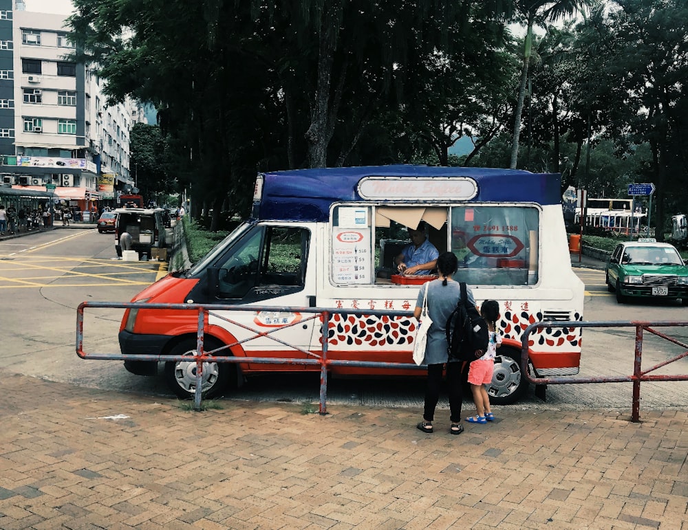 a man and a little girl standing in front of a food truck