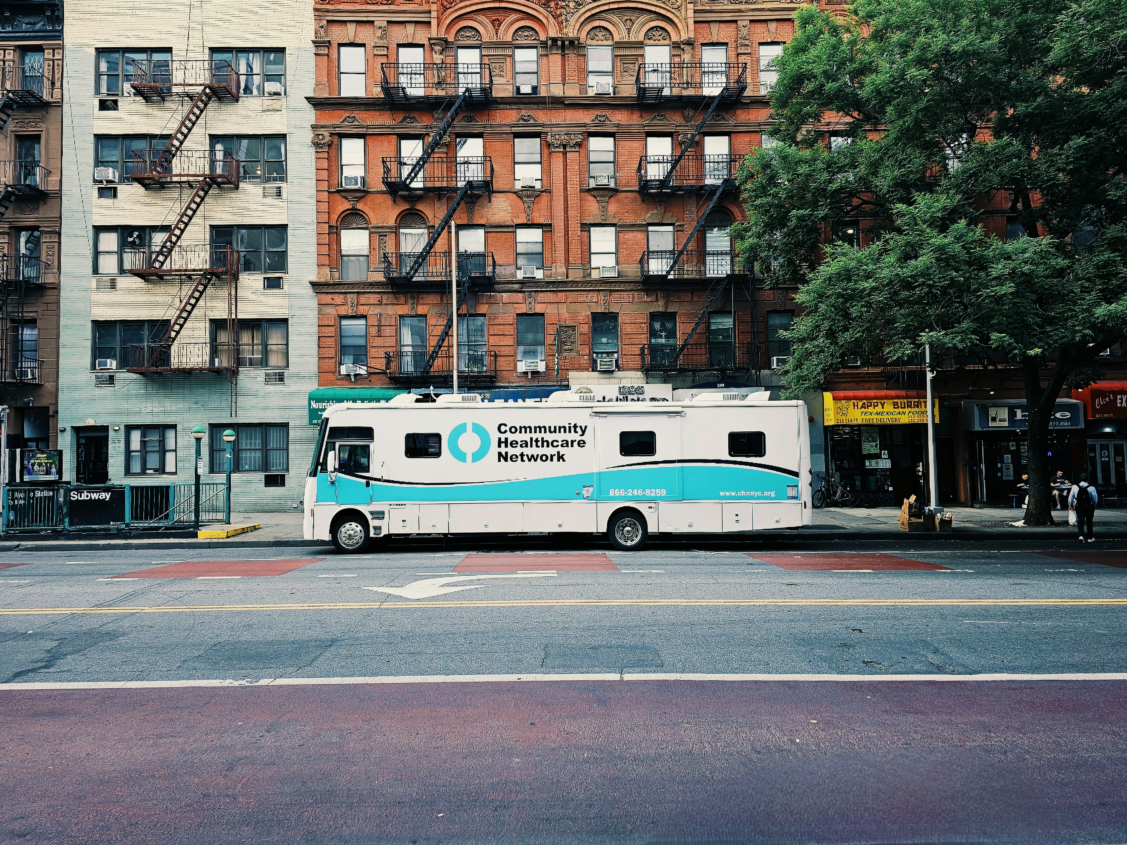 a white and blue bus parked in front of a tall building