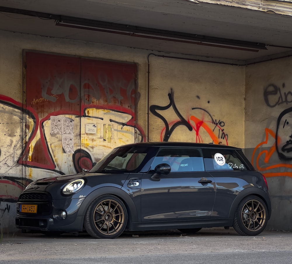 a small car parked in front of a graffiti covered wall
