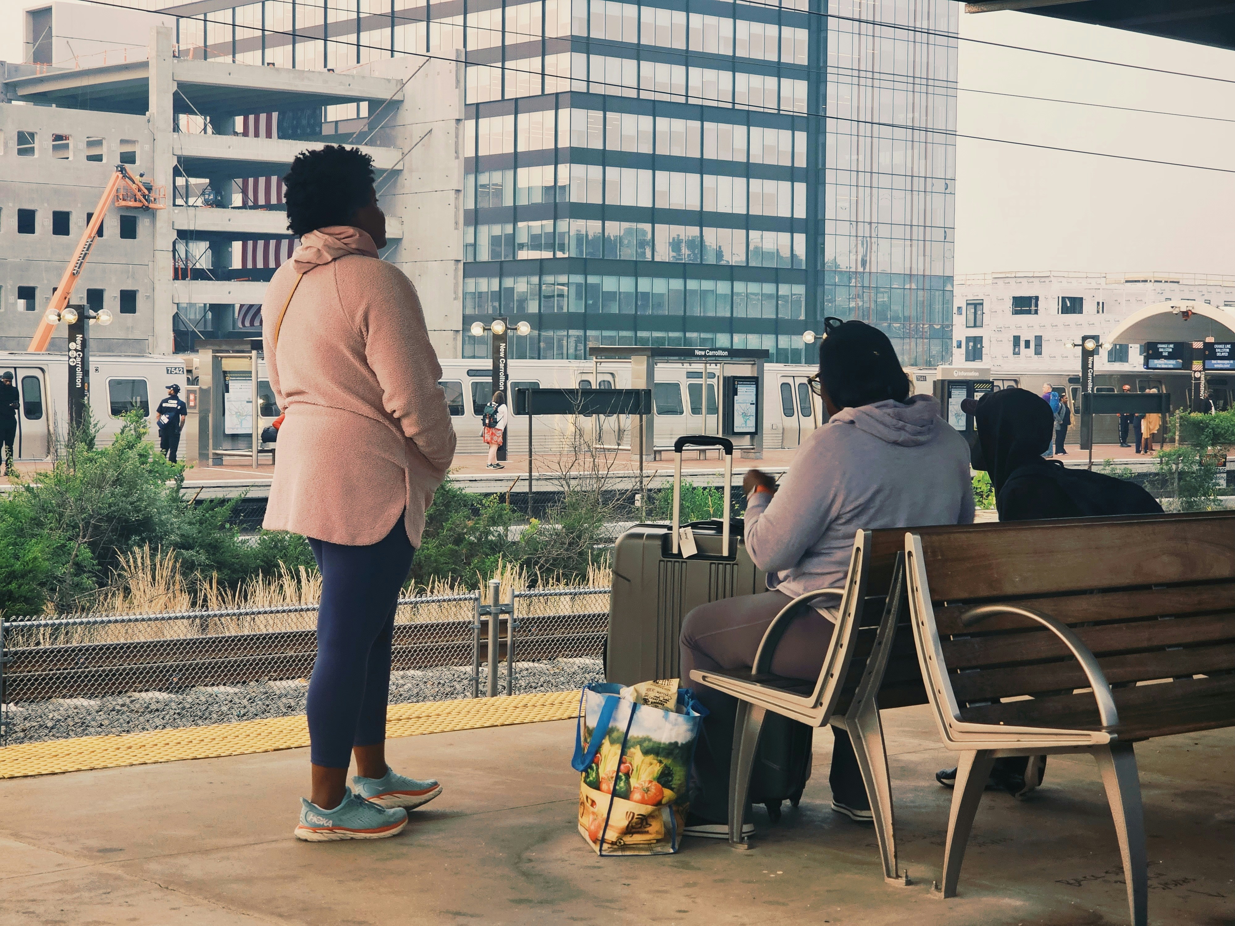 a woman standing next to a woman sitting on a bench