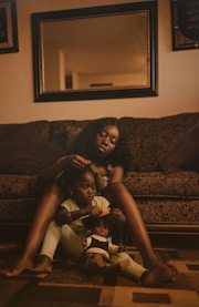 two women sitting on the floor in front of a couch
