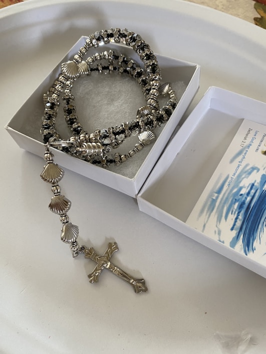 A rosary bracelet made of silver-colored beads and shells.