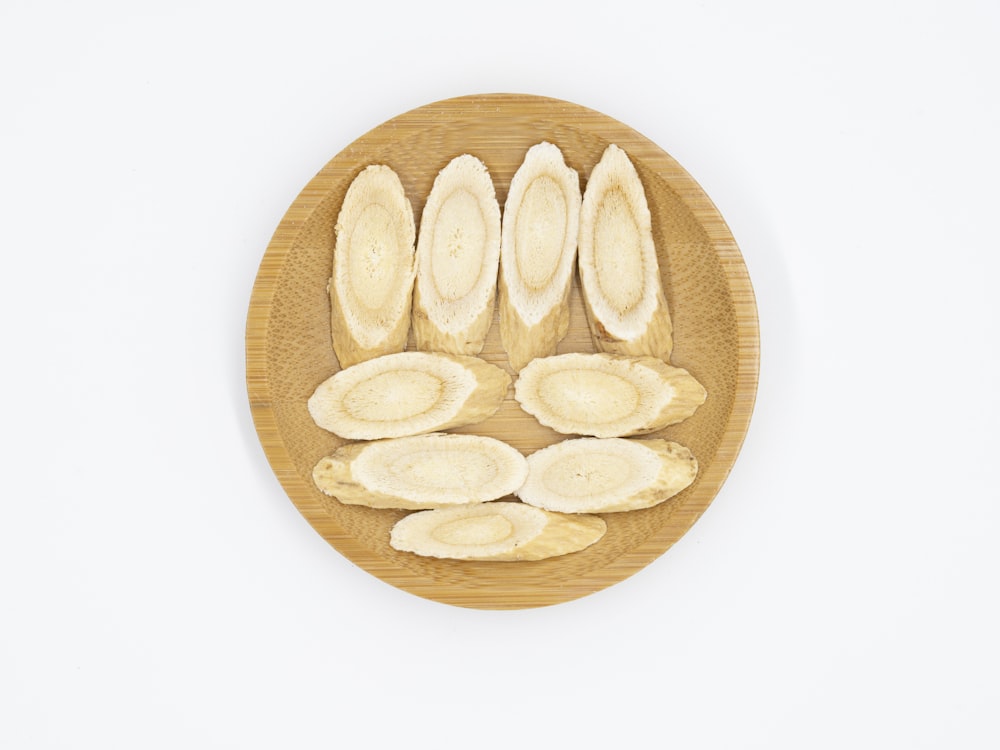 a wooden plate topped with sliced bananas on top of a white wall