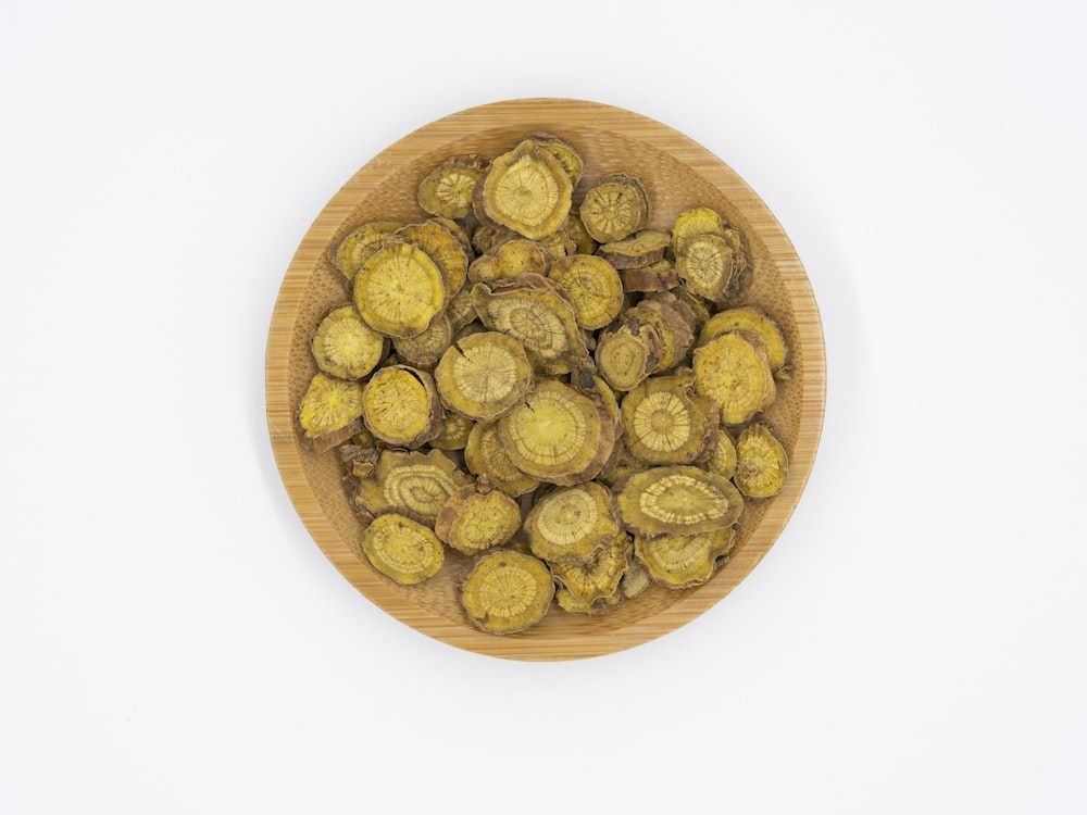 a wooden bowl filled with green vegetables on top of a white table