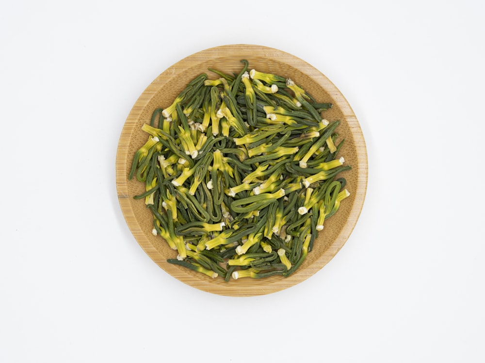 a wooden bowl filled with green beans on top of a white table