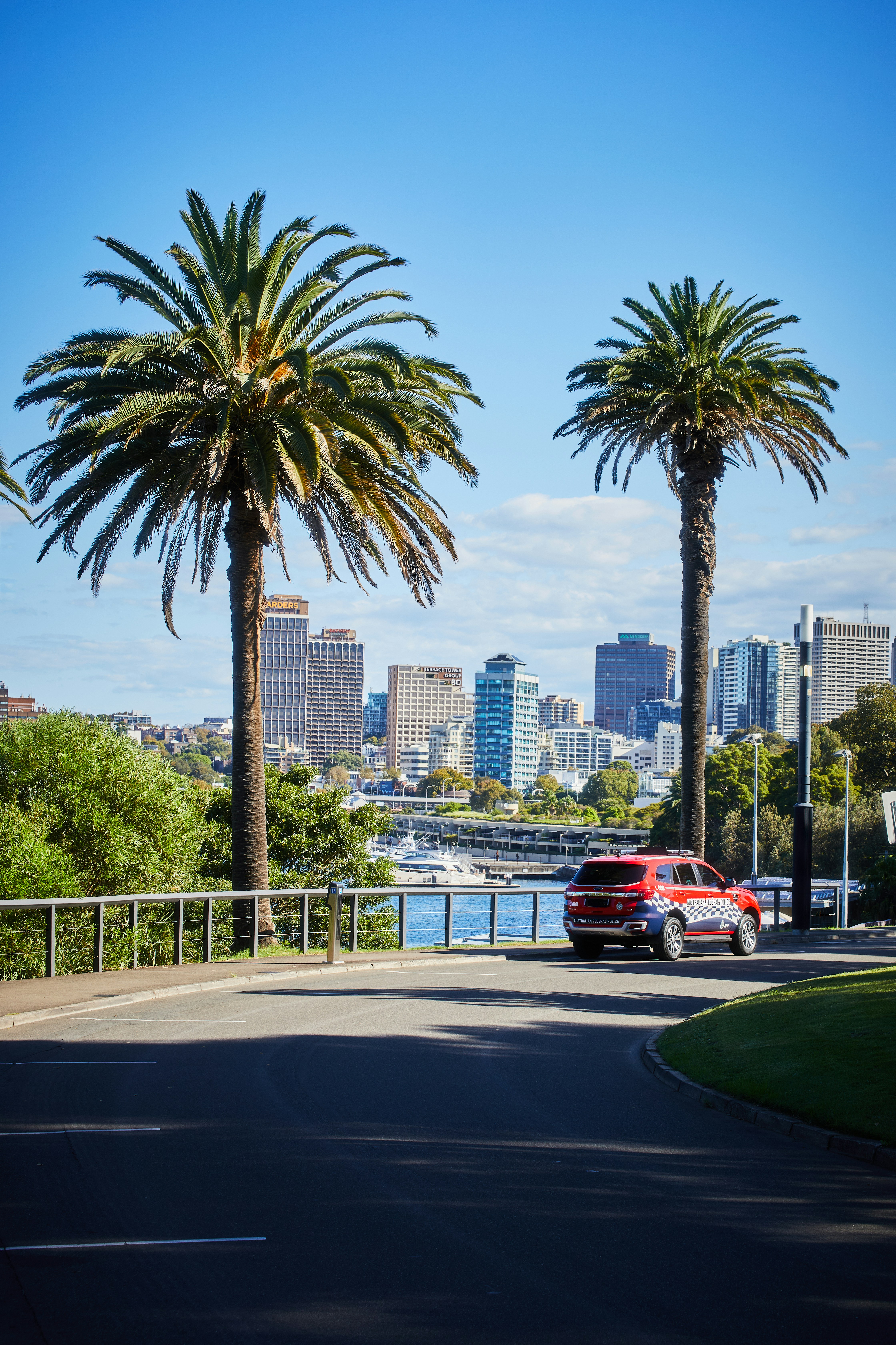 Une voiture rouge roulant dans une rue à côté de palmiers