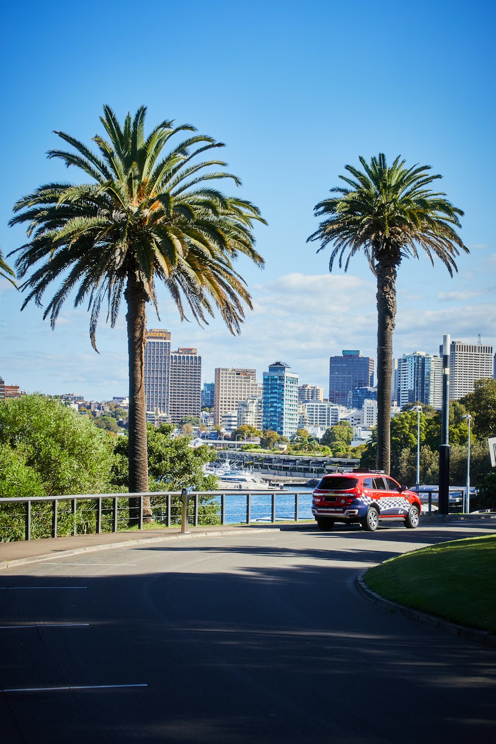 a red car driving down a street next to palm trees