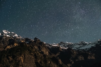 A panoramic view of a mountain range under a dramatic sky filled with stars.