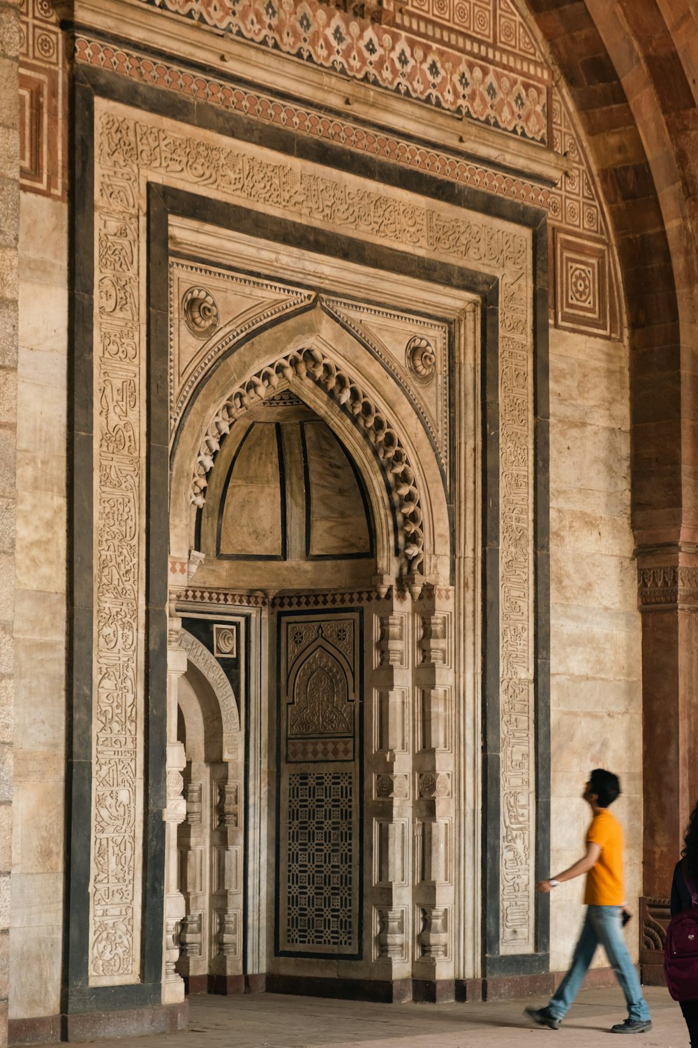 two people walking in front of an ornate doorway