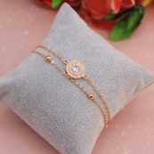 a diamond bracelet on a pillow with a rose in the background