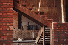 a man standing next to a brick building under construction