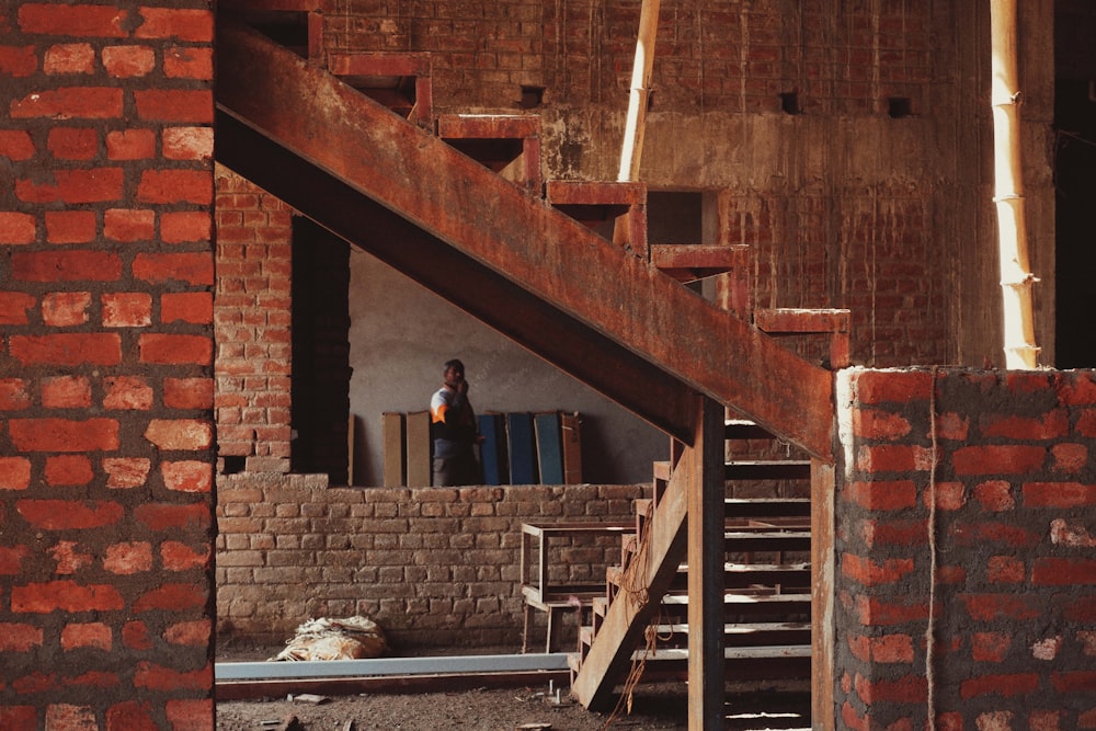 a man standing next to a brick building under construction