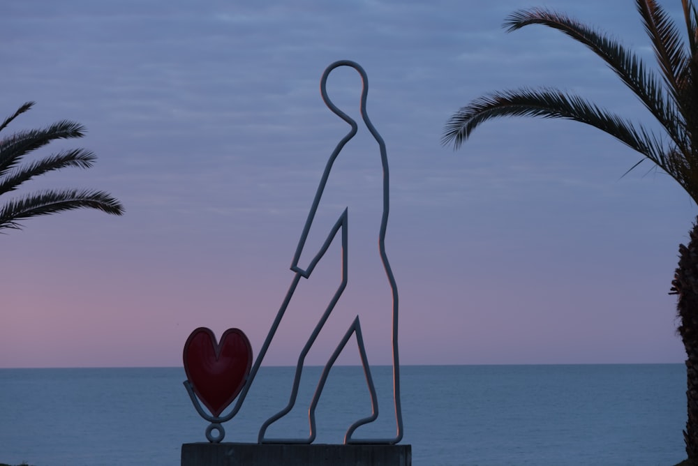 a sculpture of a man holding a heart next to a body of water