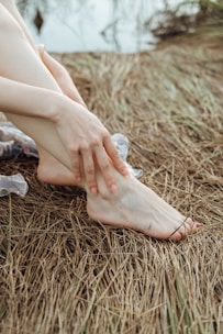 a woman's bare legs and bare feet sitting on the ground