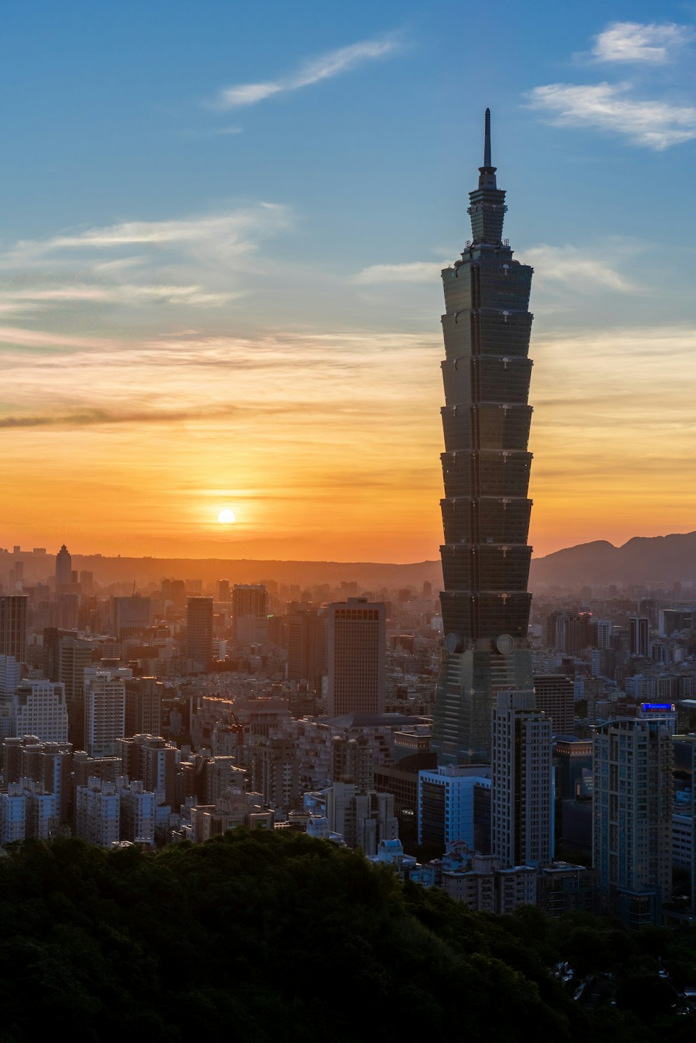 the sun is setting over a city with tall buildings