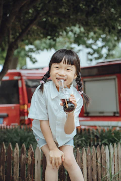 A smiling child holding a colorful bottle during a community outreach event.