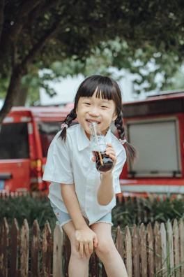 A smiling child holding a colorful bottle provided by the foundation