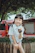 A joyful child holding a water bottle, standing beside a newly installed clean water tap in a vibrant village setting.