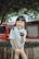 A joyful child holding a water bottle in a sunny outdoor park.