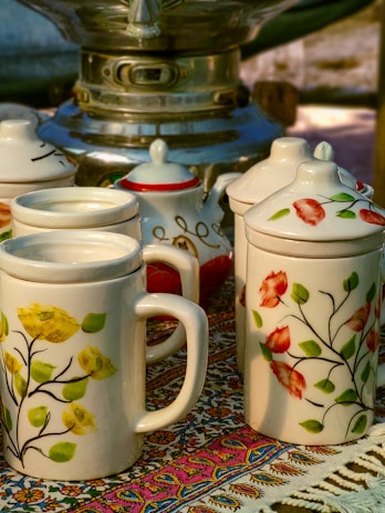a table topped with three coffee cups and a tea pot