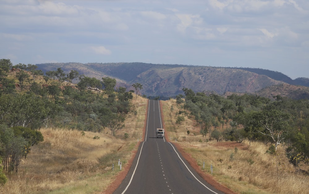 a truck driving down a road in the middle of a field