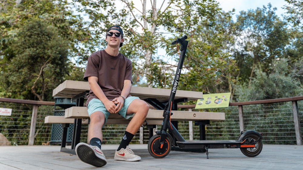 a man sitting on a bench next to a scooter