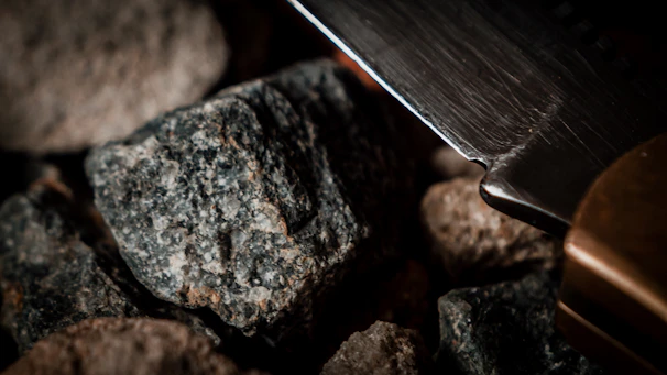 Close-up of a diamond core bit resting on rugged rock, highlighting its sharp cutting edges.